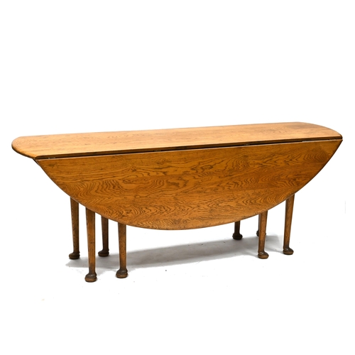 594 - A 20th Century reproduction of a Georgian style wake table in mid oak, supported on eight legs with ... 