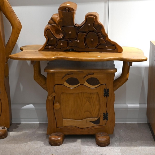 640 - A late 20th century carved oak character side table with cabinet under. The cabinet having carved ey... 