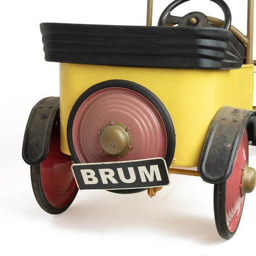 227 - A vintage Ragdoll Brum 2003 ride-on pedal car in yellow and red with pedals and crank handle, the nu... 