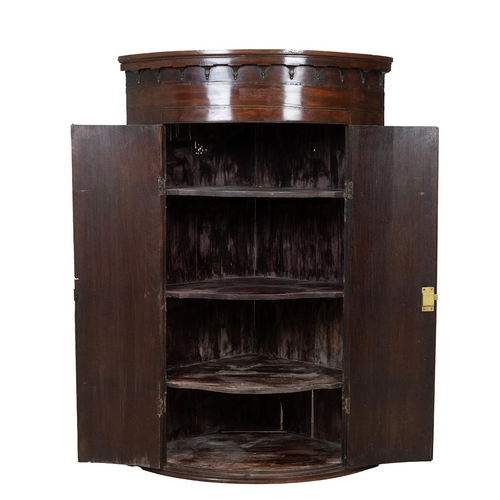 426 - Georgian mahogany bow fronted corner cupboard with ebony and boxwood stringing, castellated pediment... 