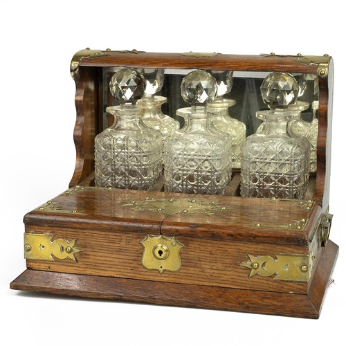 433 - Edwardian brass bound oak Tantalus with three cut glass hobnail decanters and hinged covers opening ... 