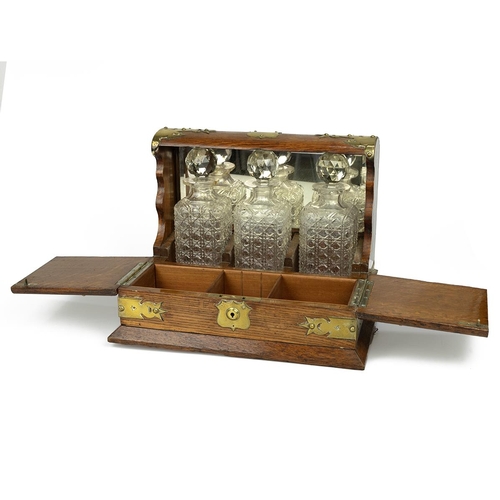 433 - Edwardian brass bound oak Tantalus with three cut glass hobnail decanters and hinged covers opening ... 