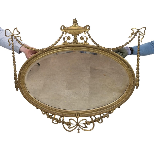 444 - Regency Adams style oval mirror, with bevelled glass, the gilt wooden frame decorated with gilt bras... 