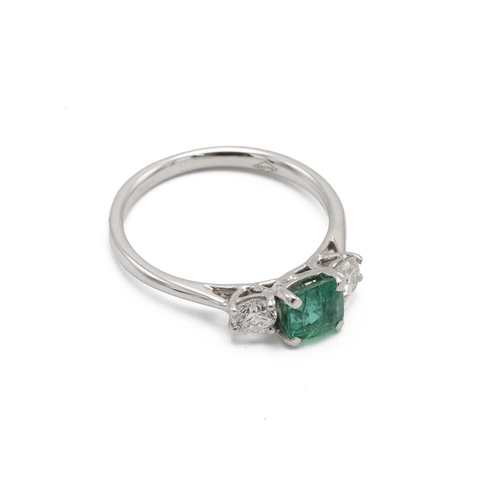 16 - Emerald and diamond three stone ring, the square cut stone flanked either side by a brilliant cut, t... 