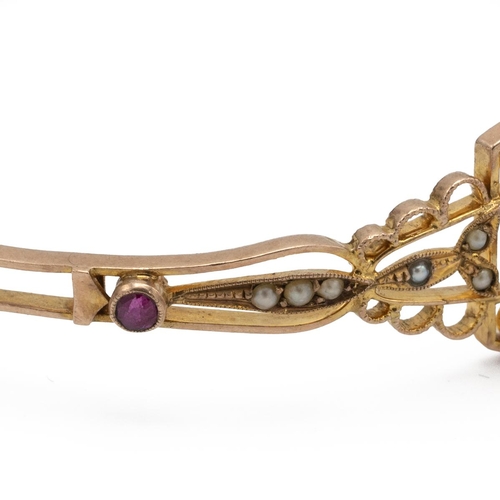 202 - An early 20th-century synthetic ruby and seed pearl hinged bangle, stamped ‘9ct’ to the catch, inner... 