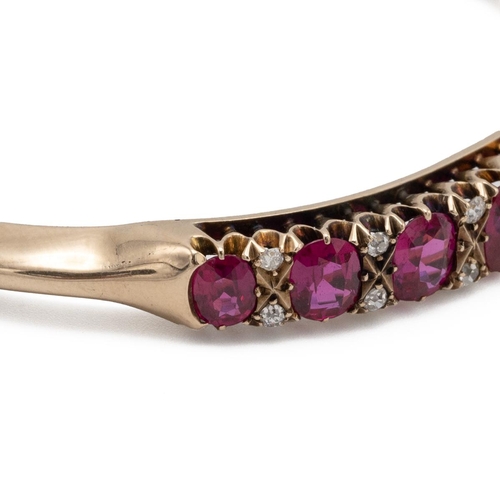 203 - An early 20th-century synthetic ruby and diamond hinged bangle, set with nine graduated oval cuts wi... 