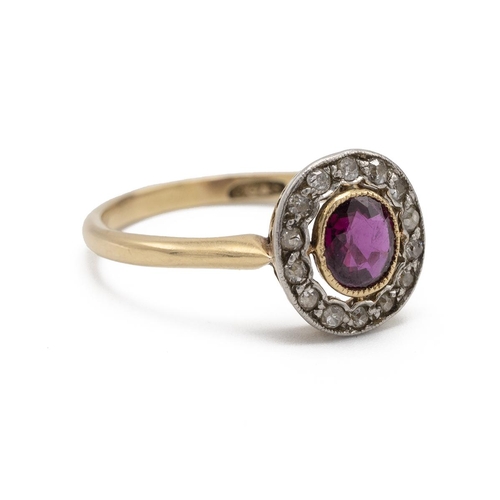 40 - An Edwardian ruby and diamond cluster ring, the oval cut stone enclosed by old single cut diamonds, ... 