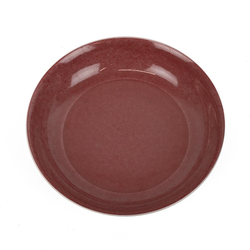 113 - A CHINESE COPPER-RED GLAZED PLATEThe well-potted rounded sides rising from a short foot to a subtly ... 