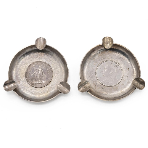 364 - PAIR OF CHINESE SILVER ASHTRAYS WITH COINS TO THE WELL.Both of circular form with dimple effect to t... 