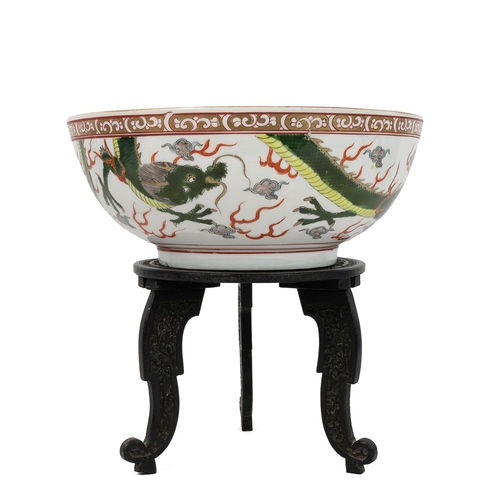 104 - AN ORIENTAL PUNCH BOWL ON WOODEN STAND, EARLY 20TH CENTURYPainted with two flying green dragons amon... 