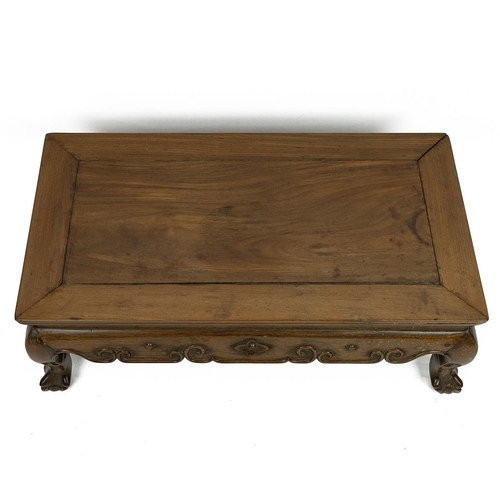 229 - A HUANGHUALI WOOD KANG TABLE, 19th CENTURY.Of rectangular form, the top above a shaped scrolled carv... 