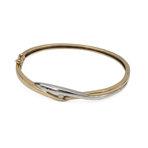 141 - Yellow and white metal bangle, set with a single brilliant cut white stone, marked '9ct', tested as ... 