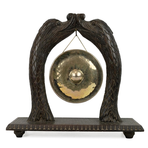 235 - Carved table gong, late 19th Century. Carved hardwood base with uprights fashioned as two mythical d... 