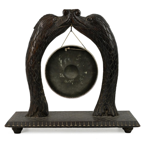 235 - Carved table gong, late 19th Century. Carved hardwood base with uprights fashioned as two mythical d... 