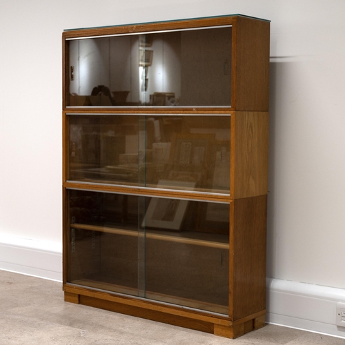 529 - Mid-century three-section teak bookcase, with original label, 117cm high, 89cm long, 24cm deep.