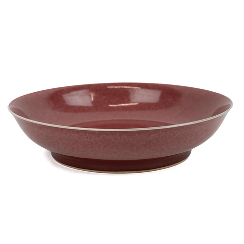239 - A Chinese copper-red glazed plate. The well-potted rounded sides rising from a short foot to a subtl... 