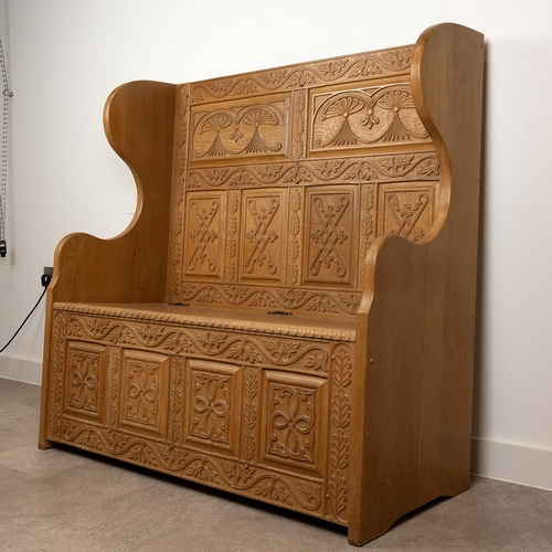 541 - Handmade peg jointed and carved oak settle with tall, profusely relief carved back and scroll shaped... 