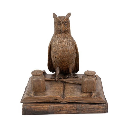 199 - Oak carving of an Owl standing on two books, early 20th century. One talon clutches a quill with an ... 