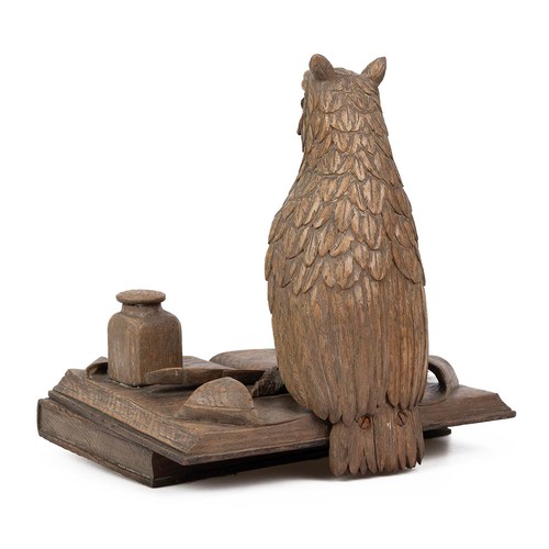 199 - Oak carving of an Owl standing on two books, early 20th century. One talon clutches a quill with an ... 