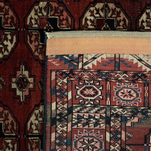 374 - A 20th-century Tekke rug, on a red ground with repeating central motifs and border,  180cm x 115cm.