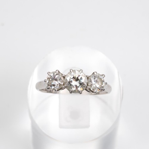 91 - A three-stone diamond ring, set in a raised platinum mount and claw setting, the central diamond app... 