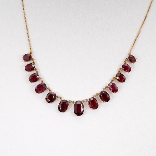 166 - A garnet set necklace the central stone flanked by twelve graduating garnets, wish 'S' shaped clasp,... 