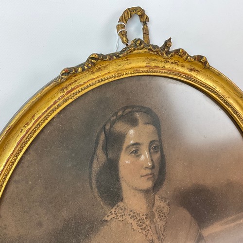 700 - A 19th century charcoal drawing of a lady, in oval plaster and gilt frame, with ribbon finial, unsig... 