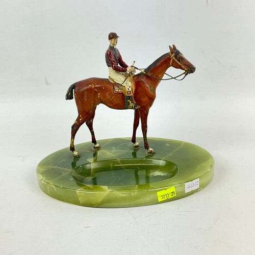 826 - A cast lead figure of a jockey on horseback, on a green onyx ashtray base. H19cm X W22cm X16cm.