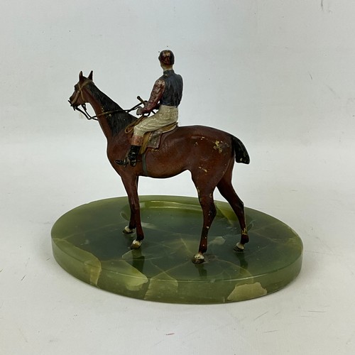 826 - A cast lead figure of a jockey on horseback, on a green onyx ashtray base. H19cm X W22cm X16cm.