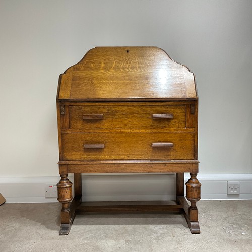 49 - An Art Deco oak bureau, of shaped form, the fall front drawer revealing fitted compartments, with tw... 