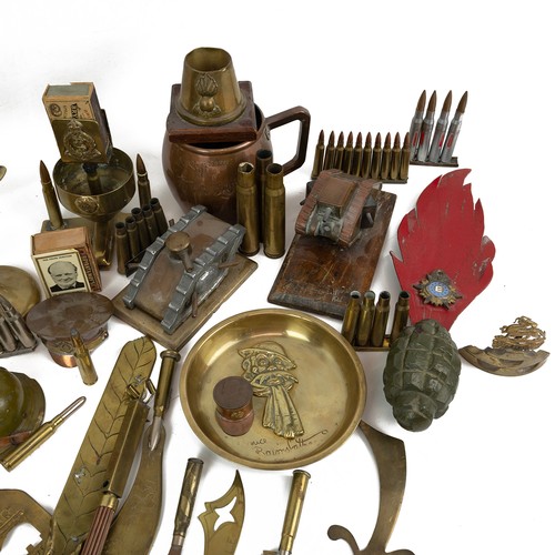 121 - A large collection of trench art, including match holders, WWI tanks, military hats, modern brass fi... 