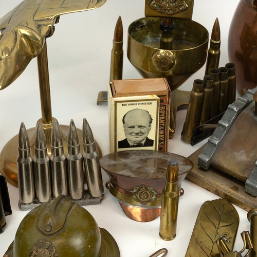 121 - A large collection of trench art, including match holders, WWI tanks, military hats, modern brass fi... 