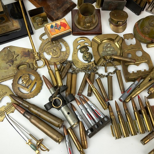 121 - A large collection of trench art, including match holders, WWI tanks, military hats, modern brass fi... 