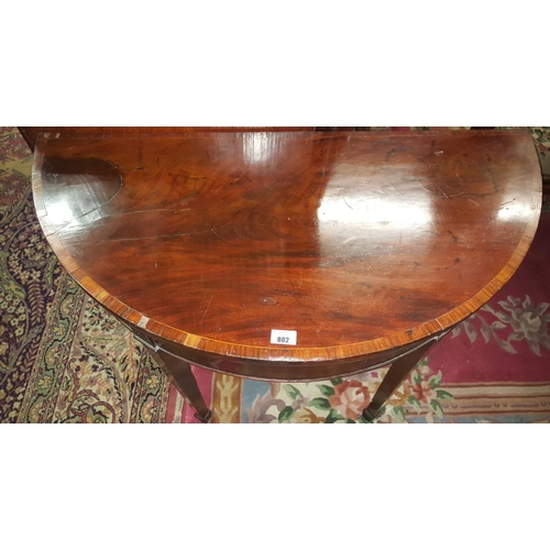 802 - A Regency Mahogany Fold over Card Table with a Kingwood Crossbanded top and with tapered supports.