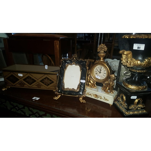 91 - A decorative Mantle Clock with Sphinx supports, an Ebonised and Gilt urn along with a metal centre p... 