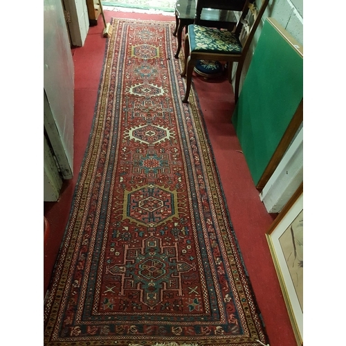 36 - A Persian runner with lozenge medallions on a red ground.