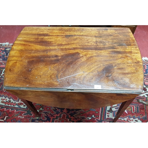 20 - A lovely Regency Mahogany Drop Leaf Table of oval form on tapered supports and brass casters.