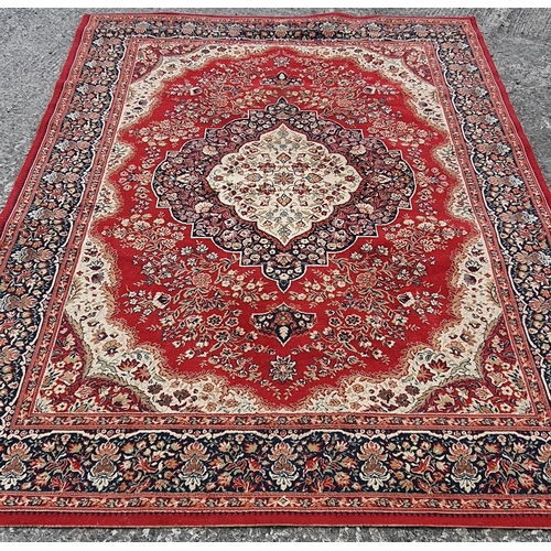 498 - A large Red ground machine made Carpet with multi borders. Slight wear and staining. 338 x 250 cm.