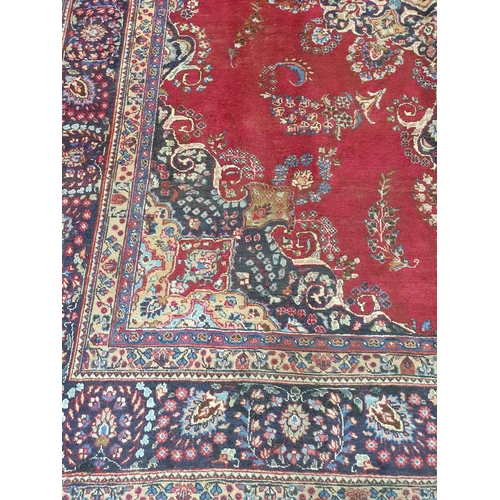 1041 - A large vintage Persian Kerman Carpet with red ground and a central medallion design. Some wear and ... 