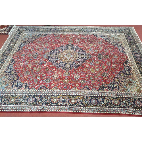 825 - A large red ground Persian Marshad Carpet with, multi coloured with a central medallion design. 380 ... 