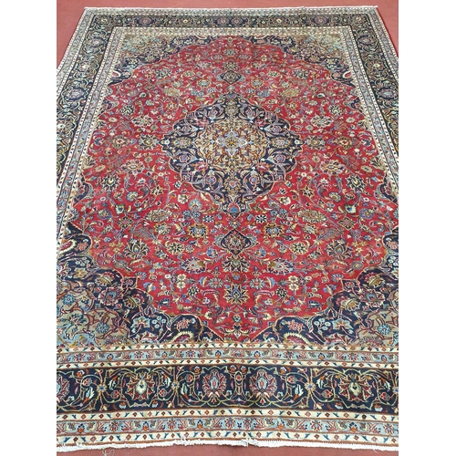 825 - A large red ground Persian Marshad Carpet with, multi coloured with a central medallion design. 380 ... 