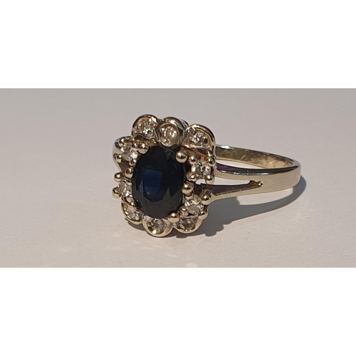 301 - A sapphire and brilliant-cut diamond cluster ring. Stamped 585. Ring size P1/2. 3.2gms.