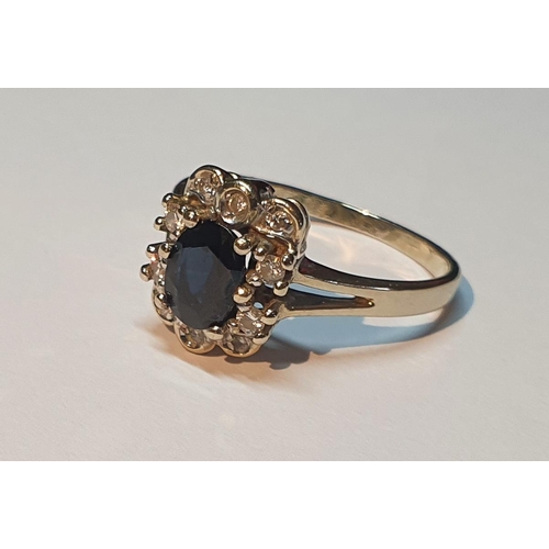 301 - A sapphire and brilliant-cut diamond cluster ring. Stamped 585. Ring size P1/2. 3.2gms.
