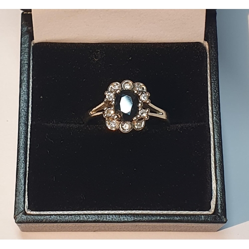 301 - A sapphire and brilliant-cut diamond cluster ring. Stamped 585. Ring size P1/2. 3.2gms.