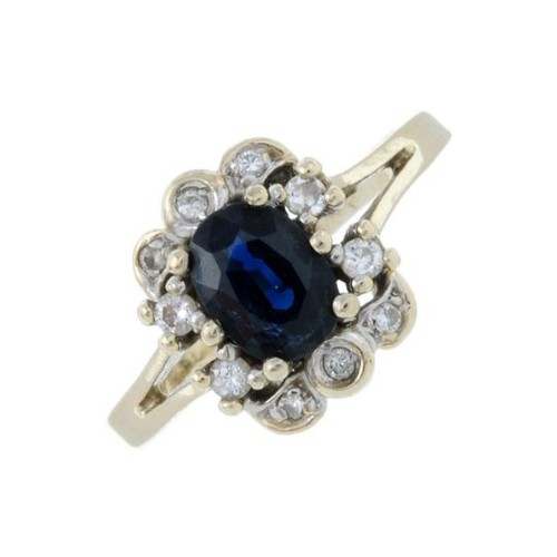 301 - A sapphire and brilliant-cut diamond cluster ring. Stamped 585. Ring size P1/2. 3.2gms.