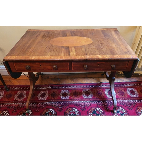 69 - A Regency Mahogany Sofa Table with an oval crossbanded top on twin splayed supports and with brass c... 