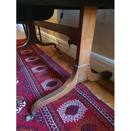 69 - A Regency Mahogany Sofa Table with an oval crossbanded top on twin splayed supports and with brass c... 