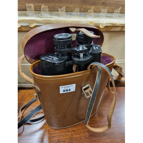 694 - The Wary Eleven. A pair of Binoculars. In a leather case.