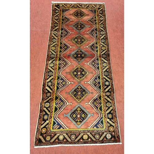 839 - A Terracotta ground Persian Mishkin Runner with a diamond medallion design. 300 x 123 cms approx.