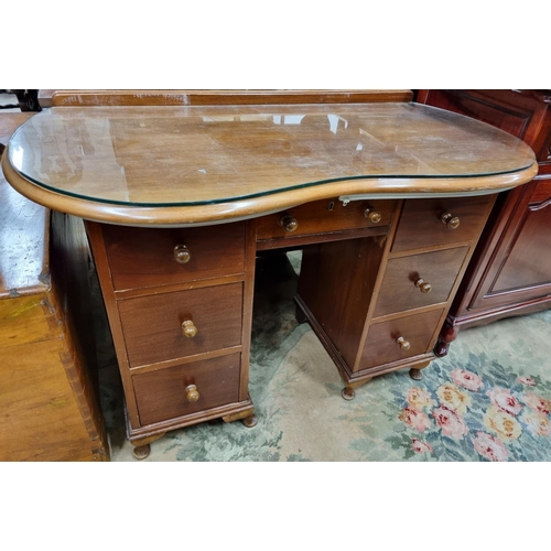 554 - A Mahogany Desk with kidney shaped top over an arrangement of seven frieze drawers raised on squat c... 